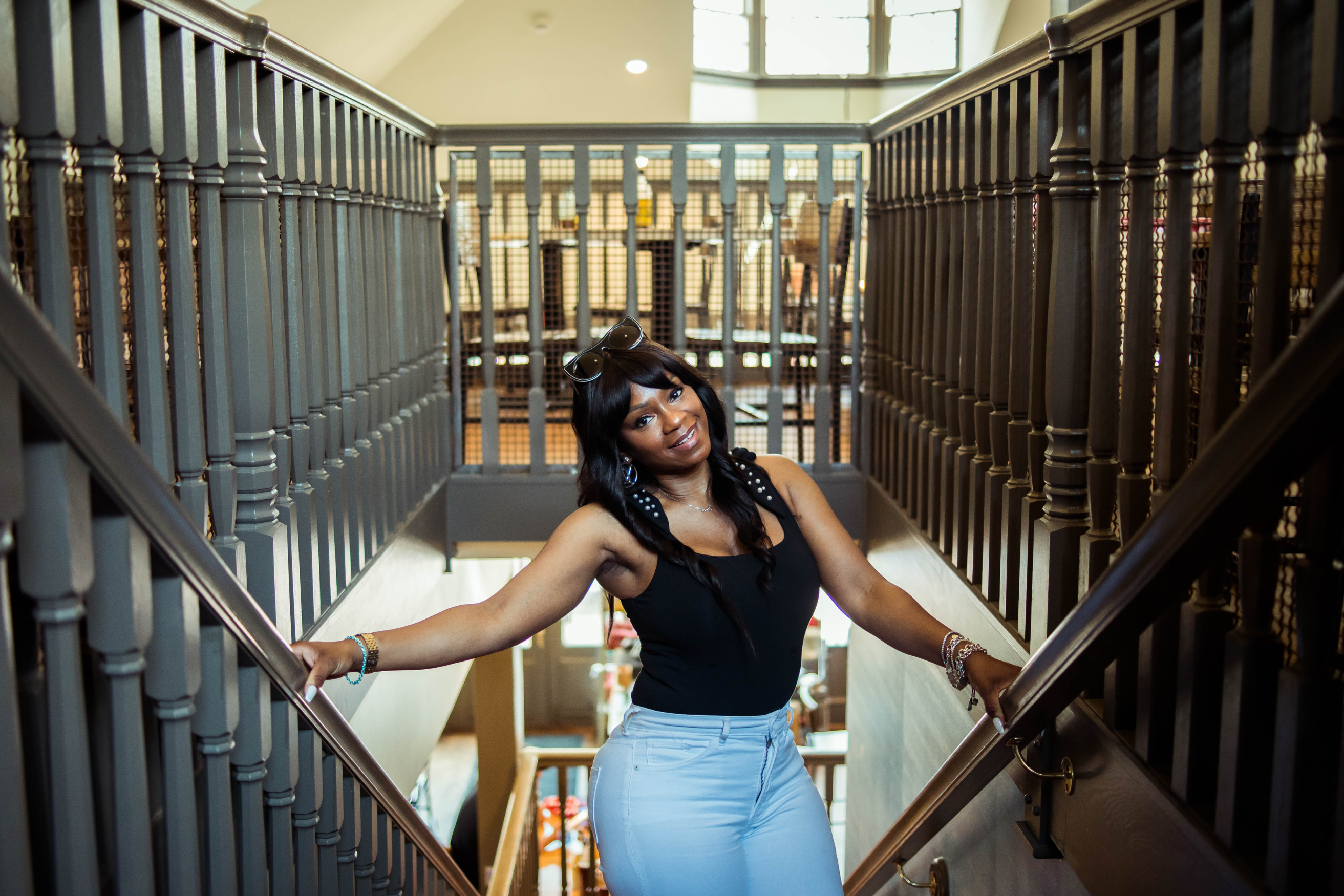 Ashocki standing on a staircase tilting her head to the right and looking at the camera.